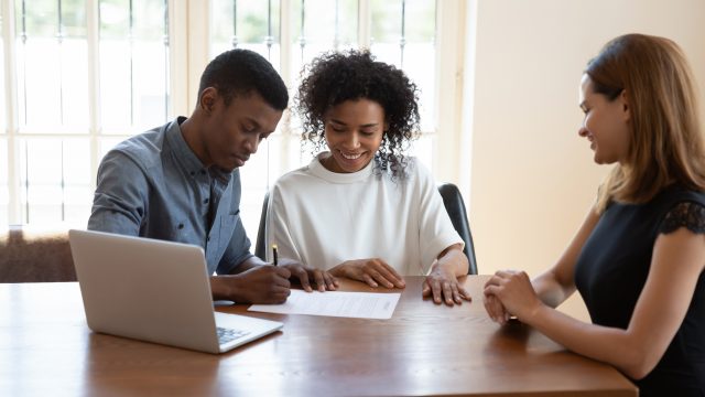 African American Couple Signing Closing Documents with Realtor