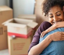 Person hugging partner with moving boxes in the background
