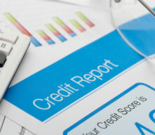 Credit report on a desk with a calculator and glasses