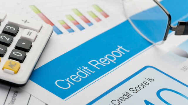 Credit report on a desk with a calculator and glasses