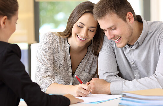 Young couple signing a documents together at office