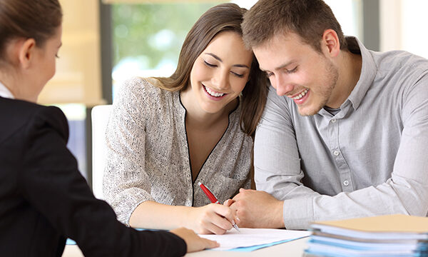 Young couple signing a documents together at office