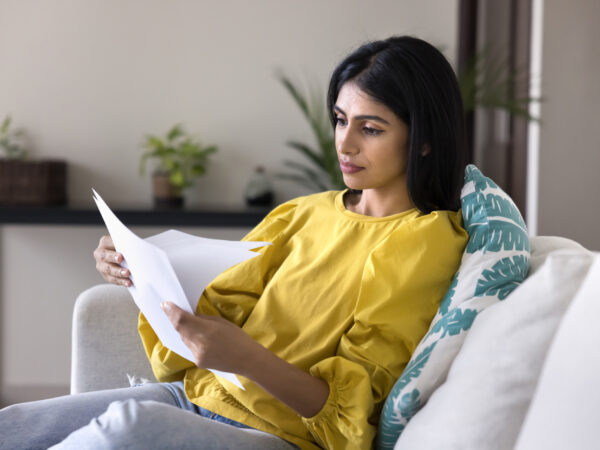 Woman sitting on couch reviewing her mortgage statement.