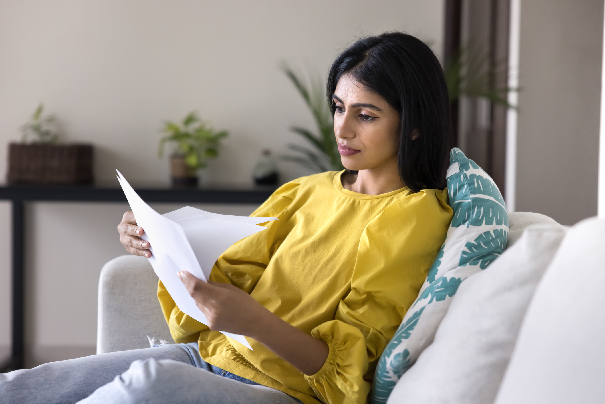 Woman sitting on couch reviewing her mortgage statement.