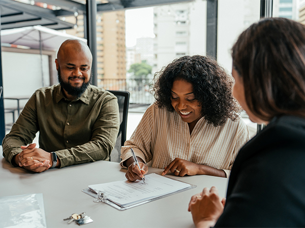 Husband and wife sitting at a table signing mortgage paperwork in attorney's office